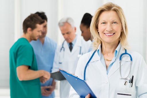 Happy Female Doctor Standing In Front Of Her Co-worker