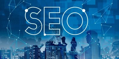 Illustration showing the word “SEO” connected to multiple strategic points with lines, set against a silhouette of real estate buildings, representing AI-driven seo for builders and modern digital visibility in search.
